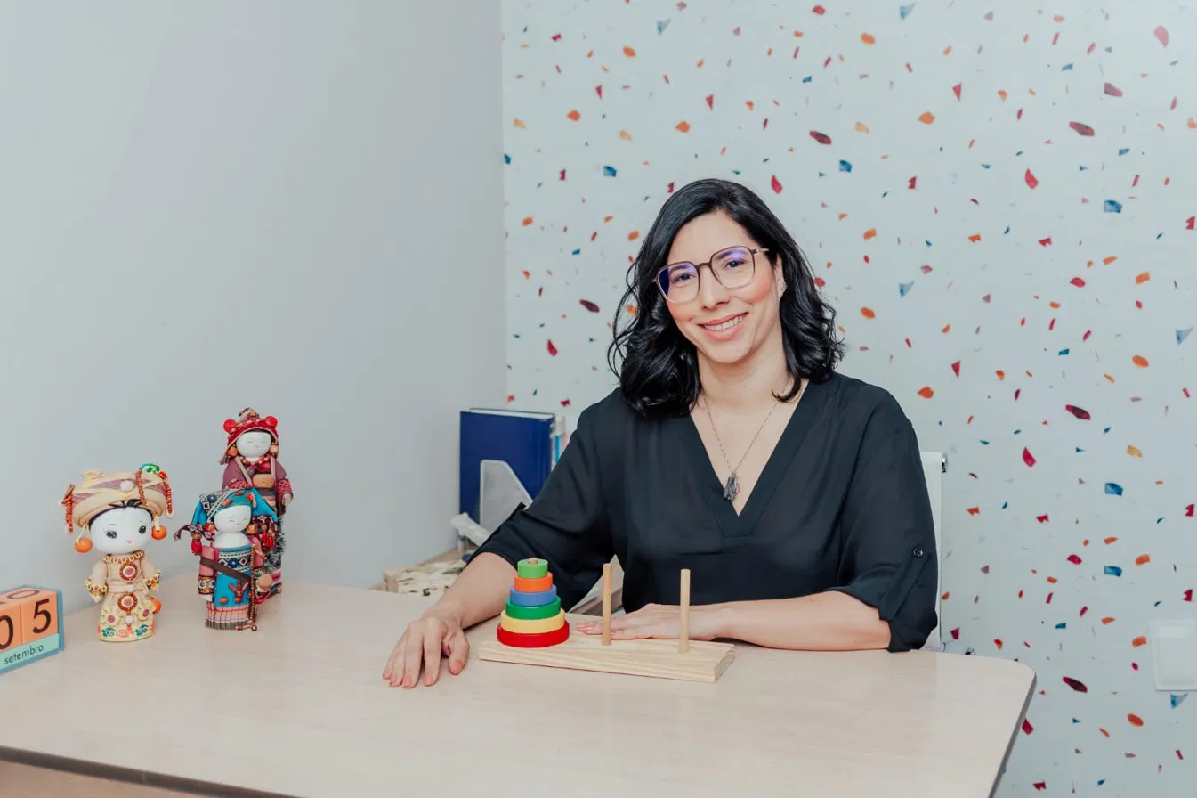 Veruska Veloso à mesa com materiais lúdicos de avaliação infantil